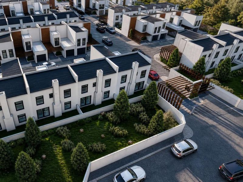 Aerial view of a modern residential estate featuring contemporary townhouses with pitched roofs, landscaped gardens, and paved access roads.