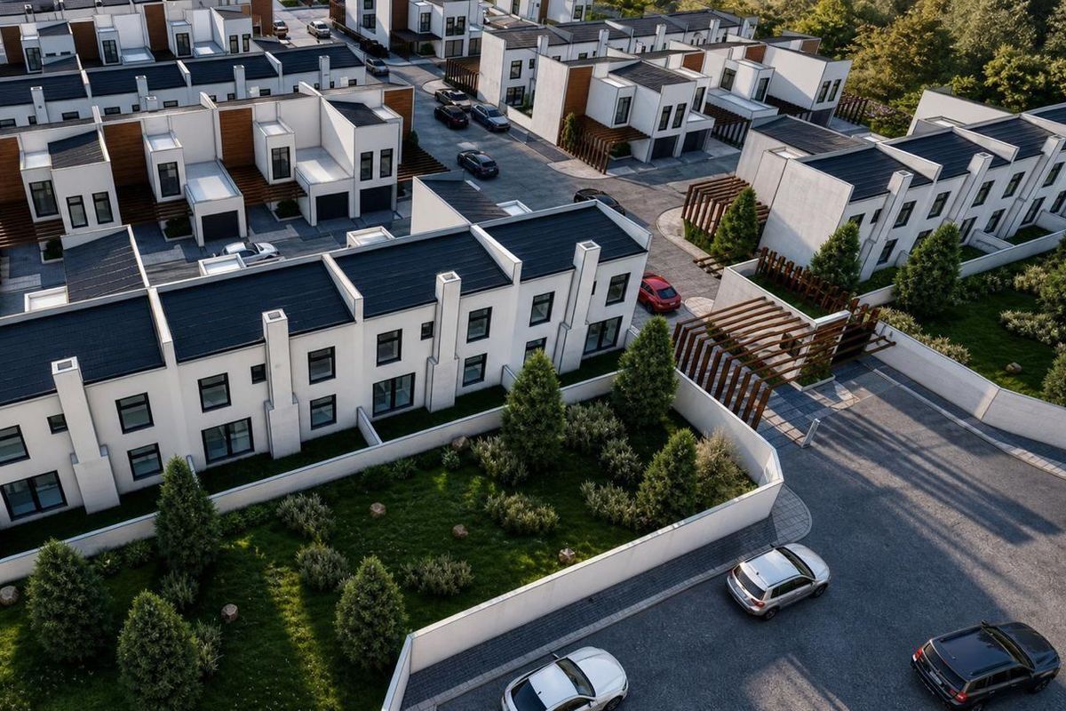Aerial view of a modern residential estate featuring contemporary townhouses with pitched roofs, landscaped gardens, and paved access roads.