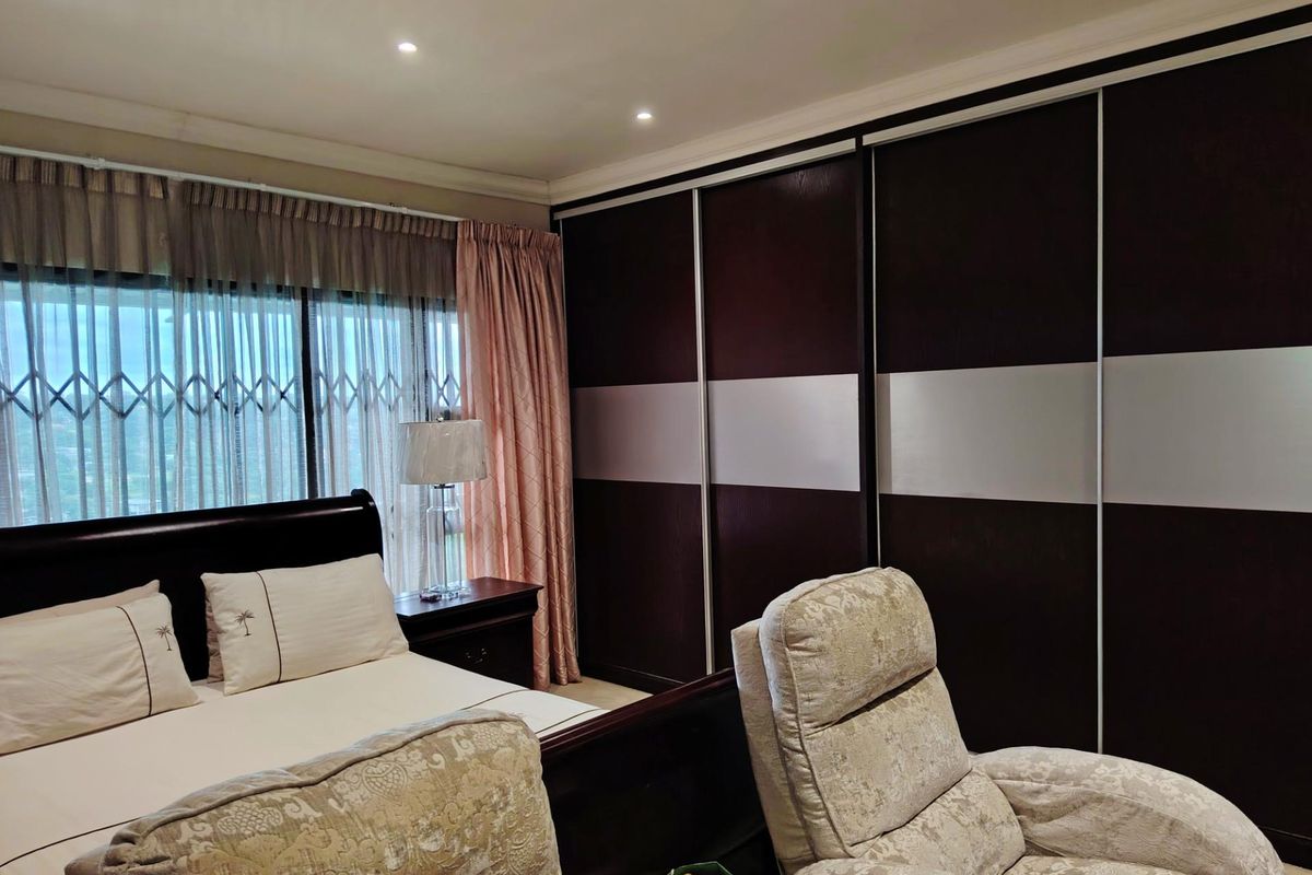A well-maintained bedroom featuring large built-in sliding door wardrobes and recessed ceiling lighting.