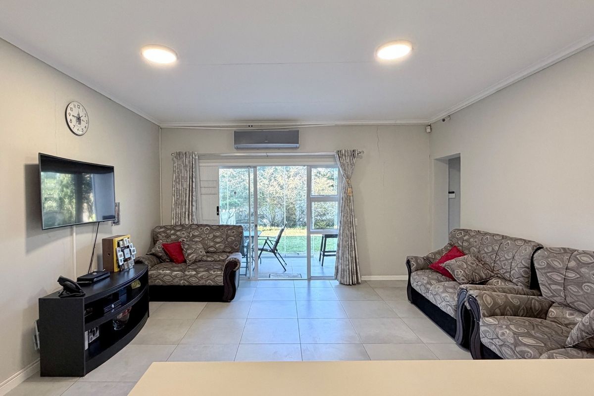 Spacious living area featuring tiled flooring, a wall-mounted air conditioning unit, and sliding glass doors providing access to the outdoor patio.