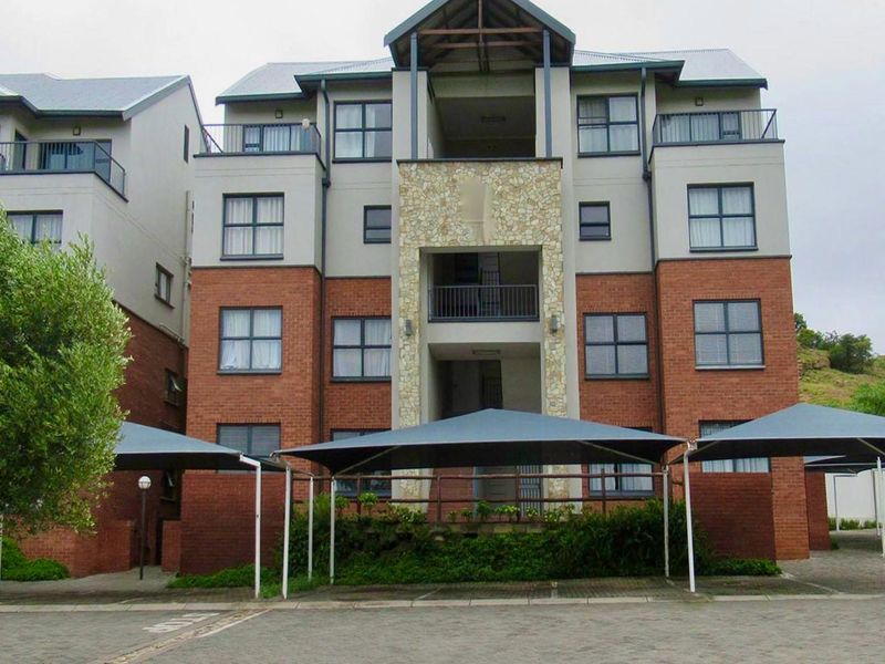 Exterior view of a multi-story apartment complex featuring brick and stone facade detailing, covered parking bays, and private balconies.