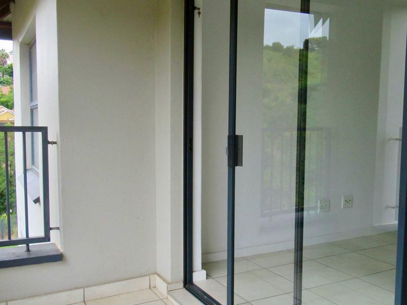 A covered balcony featuring tiled flooring and a metal railing, providing an outdoor extension to the interior living space.