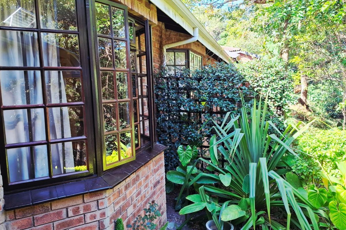 A view of the exterior brick facade featuring bay windows and established garden landscaping.