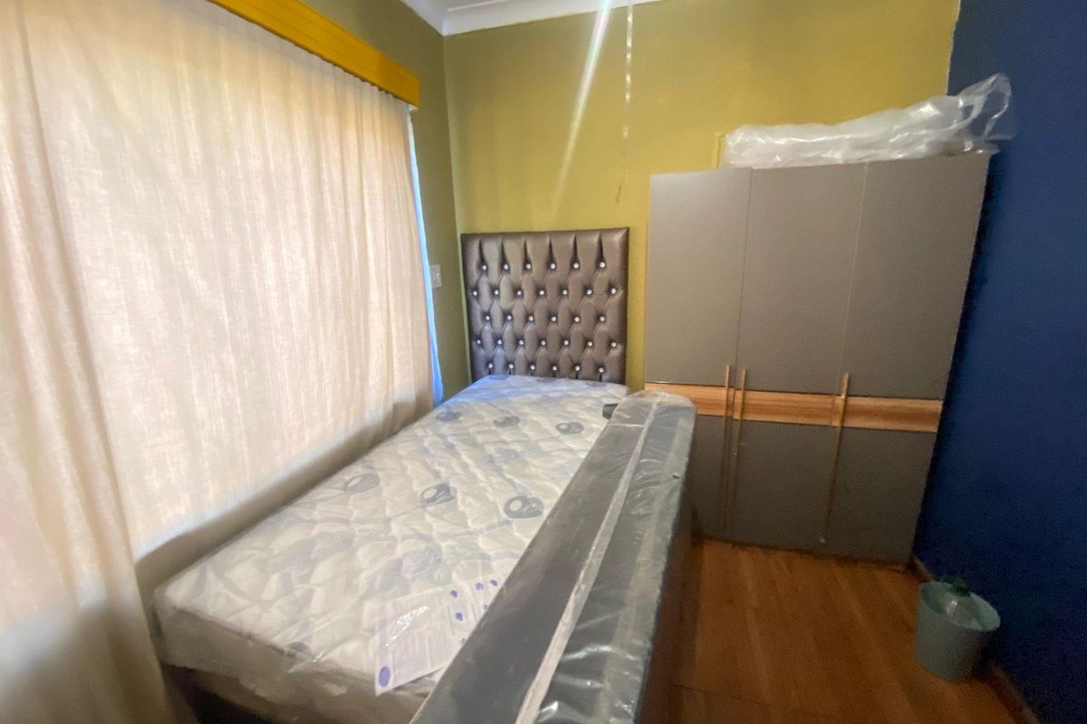 A bedroom featuring wood-look flooring, a built-in wardrobe, and a window with curtain pelmet.