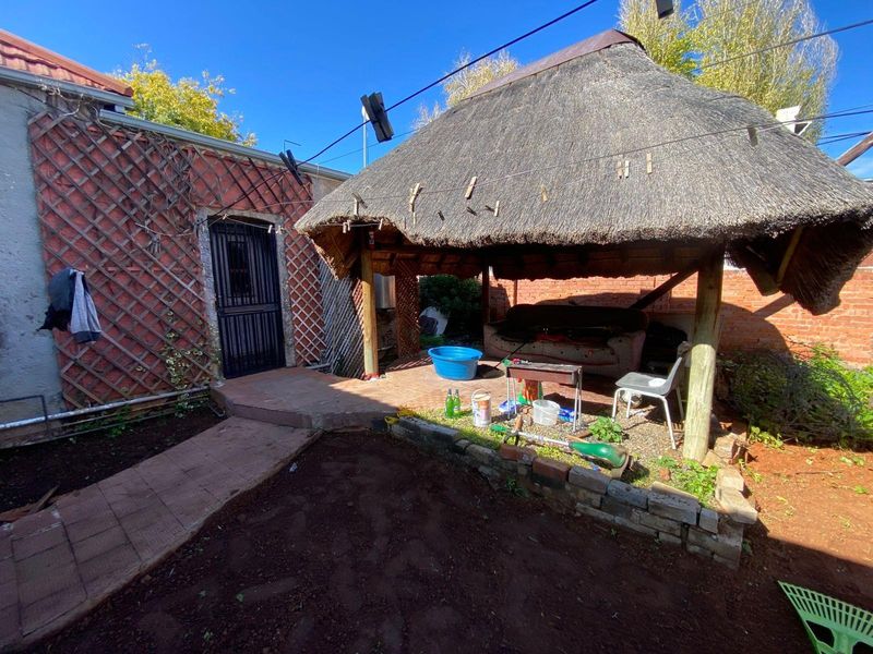 Outdoor entertainment area featuring a thatched lapa structure, brick paving, and direct access to the main dwelling.