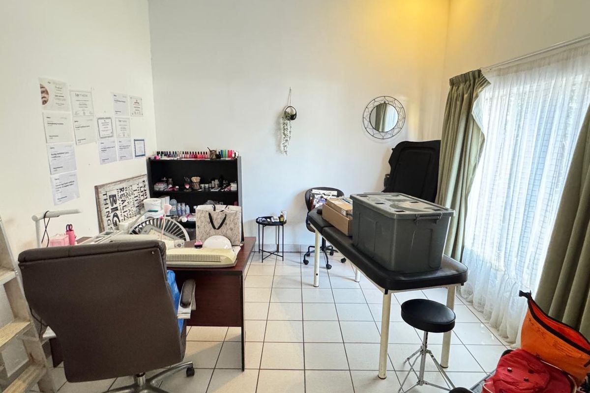 A functional room featuring tiled flooring and large windows with curtains, currently utilized as a workspace.