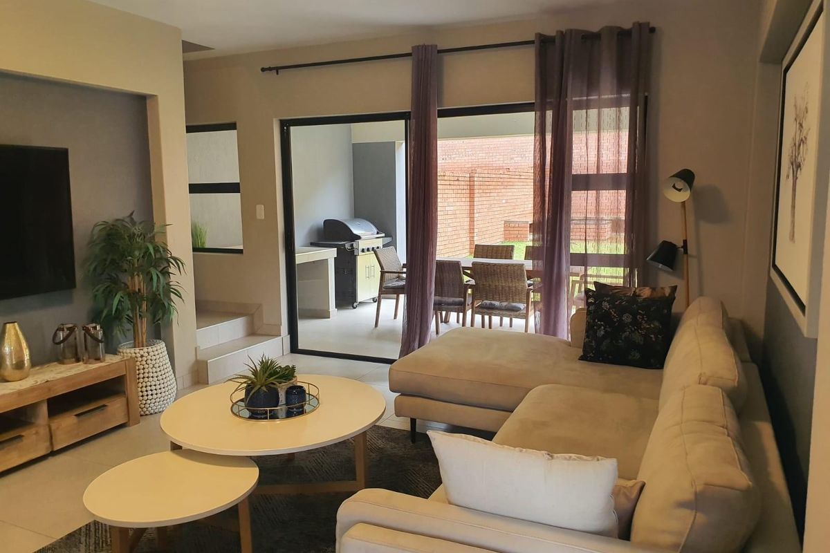 A well-maintained living room featuring a recessed media wall and large sliding glass doors that provide seamless access to the outdoor patio area.