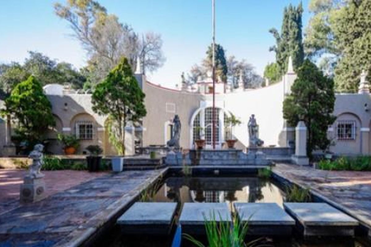 A courtyard featuring a central decorative pond, stone paving, and classical architectural elements, surrounded by a curved building facade with arched windows.