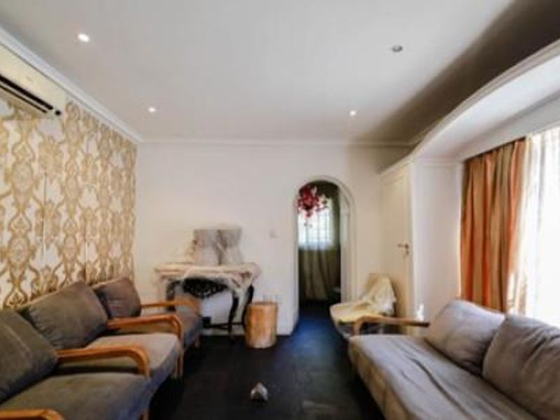 A living room featuring patterned wallpaper, recessed ceiling lighting, and an arched doorway leading to an adjacent space.