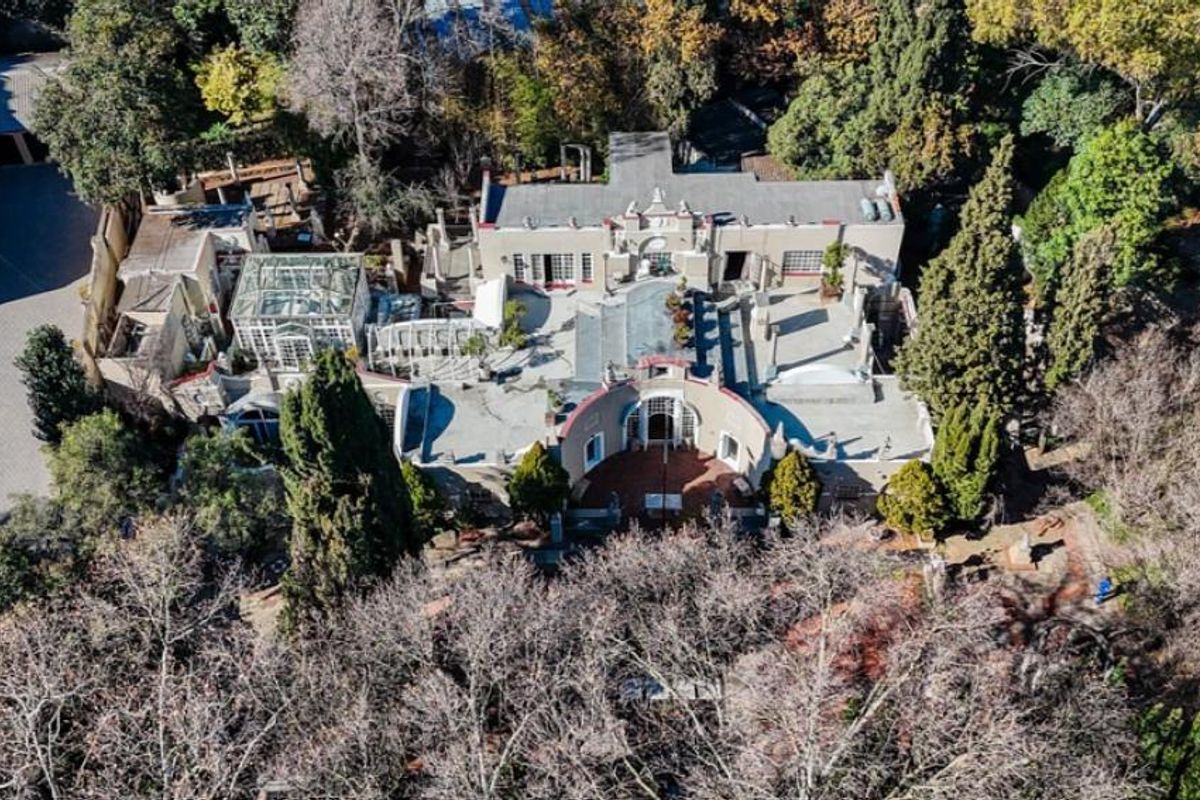 Aerial view of a large commercial property featuring multiple interconnected buildings, courtyards, and extensive landscaped grounds with mature trees.