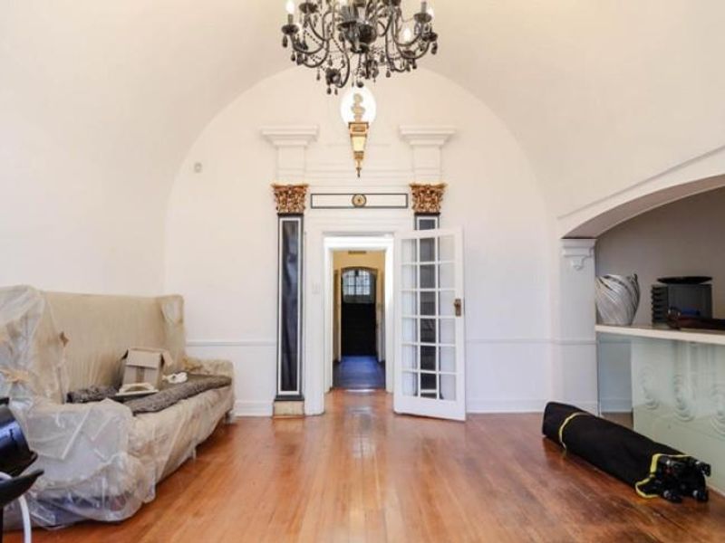 A spacious room featuring a barrel-vaulted ceiling, ornate architectural columns, a built-in service counter, and polished wooden flooring.