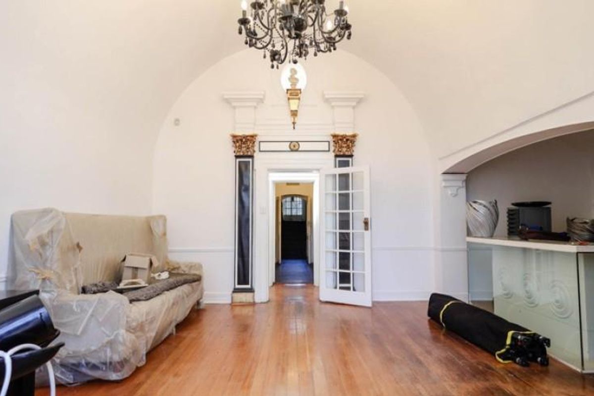 A spacious room featuring a barrel-vaulted ceiling, ornate architectural columns, a built-in service counter, and polished wooden flooring.