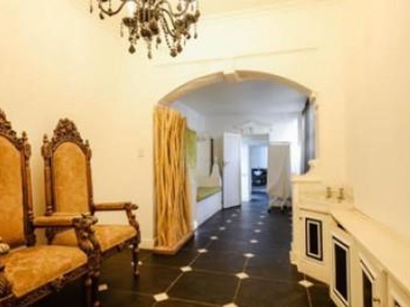 A spacious hallway featuring dark tiled flooring with white accents, an arched entryway, and built-in cabinetry, leading into an adjacent room.