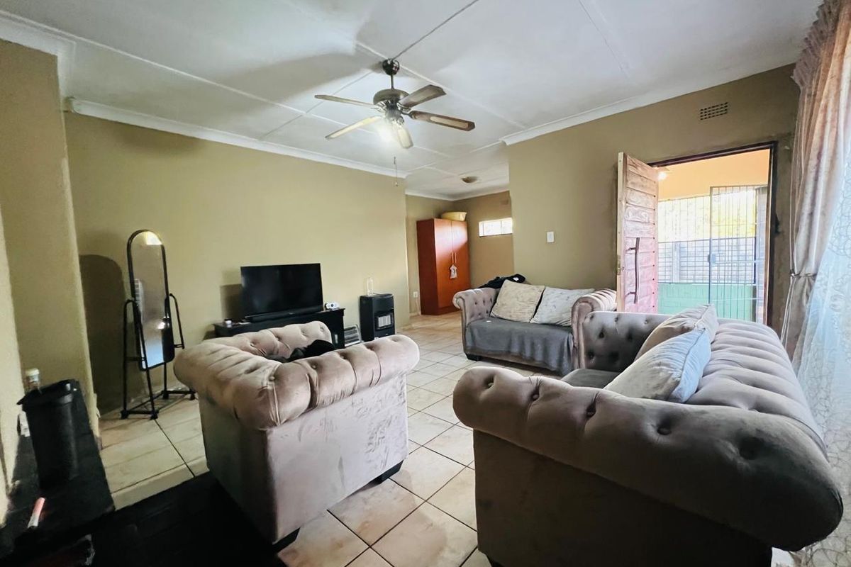A living room featuring tiled flooring, a ceiling fan, and direct access to an outdoor area through a wooden door.