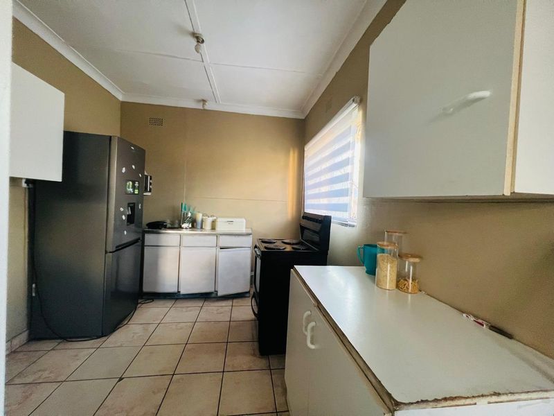 A functional kitchen featuring basic cabinetry, tiled flooring, and a freestanding stove, offering a practical layout with potential for modernization.