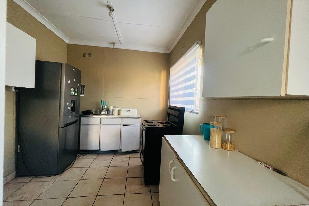 A functional kitchen featuring basic cabinetry, tiled flooring, and a freestanding stove, offering a practical layout with potential for modernization.