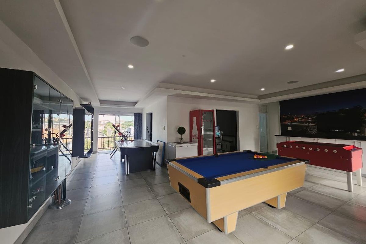 Spacious entertainment room featuring large format floor tiles, recessed ceiling lighting, and access to a balcony area.