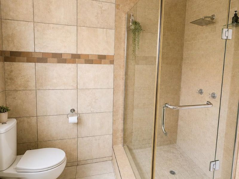 A modern bathroom featuring a walk-in shower with a glass enclosure, rain shower head, and neutral ceramic tiling throughout.