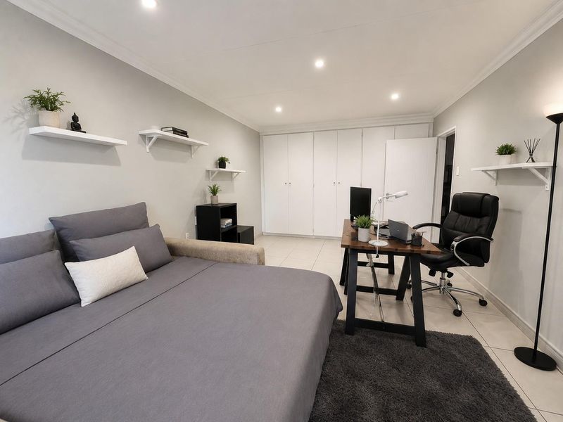 A well-maintained bedroom featuring neutral tiled flooring, recessed downlighting, and extensive built-in cupboard storage, offering a clean and functional living space.