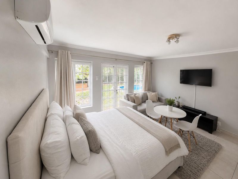 Spacious bedroom featuring tiled flooring, split-system air conditioning, and direct access to the garden through glass french doors.