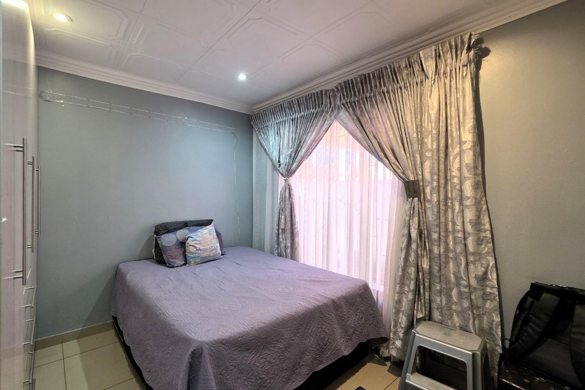 A well-maintained bedroom featuring built-in cupboards, tiled flooring, and decorative ceiling tiles with recessed lighting.