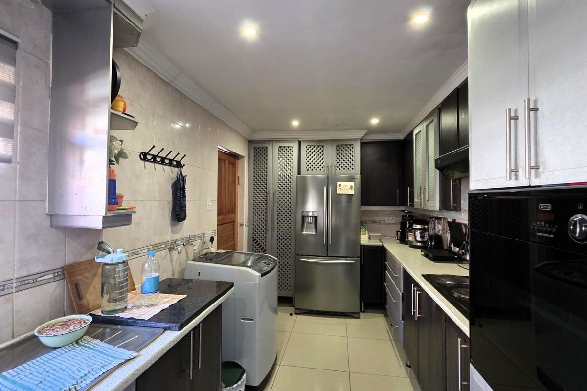 A functional kitchen featuring dark cabinetry, granite countertops, integrated appliances, and tiled flooring with recessed lighting.