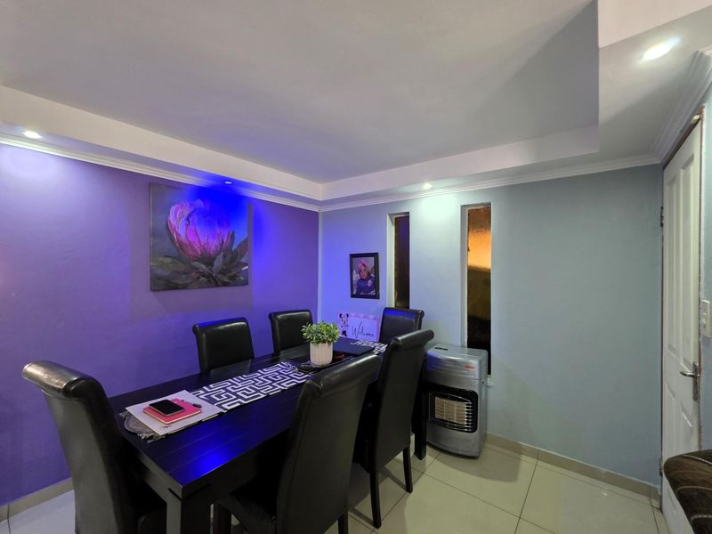 A dining room featuring tiled flooring, recessed ceiling details, and vertical windows, providing a functional space for meals.