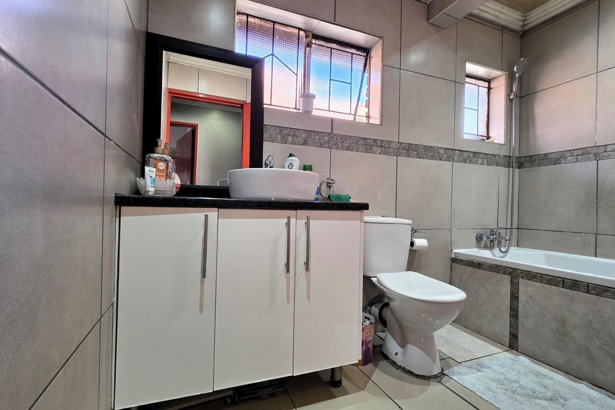A functional bathroom featuring a vanity cabinet with a vessel sink, a standard toilet, and a bathtub with wall-mounted shower fixtures.