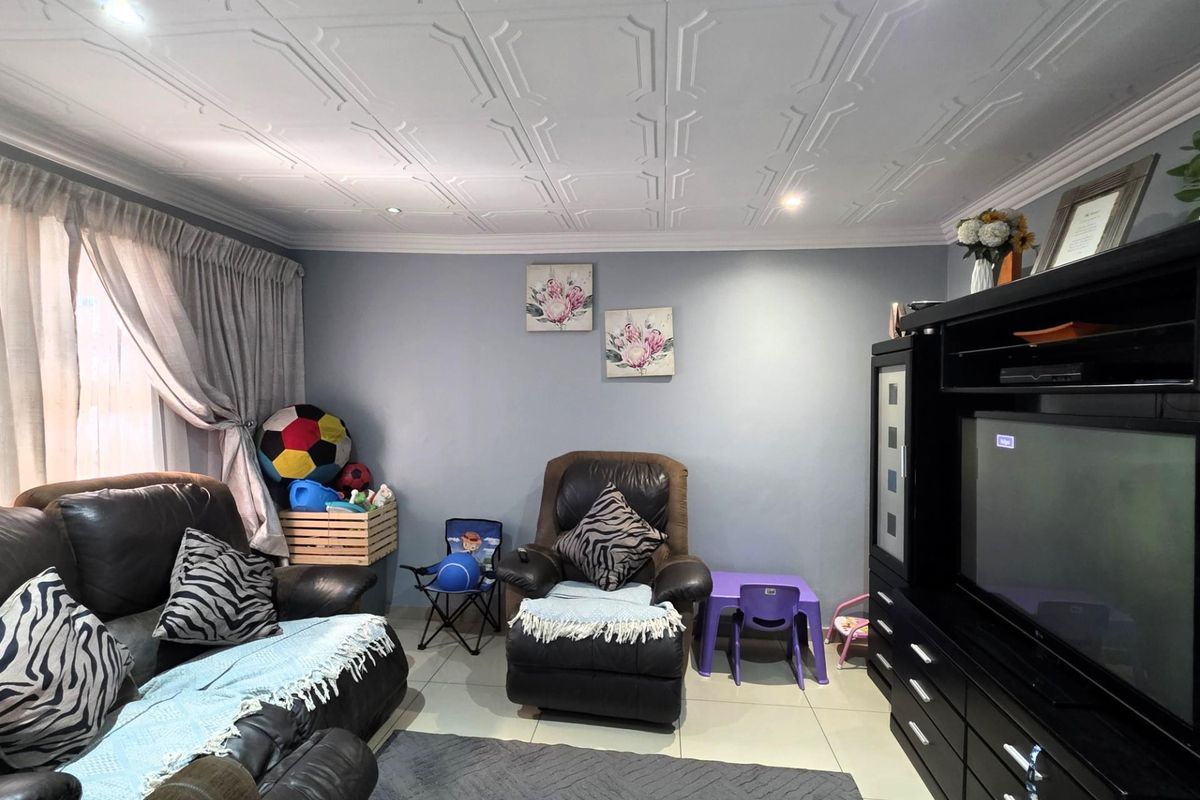 A living room featuring tiled flooring, decorative ceiling tiles, and recessed downlighting, providing a functional space for relaxation.