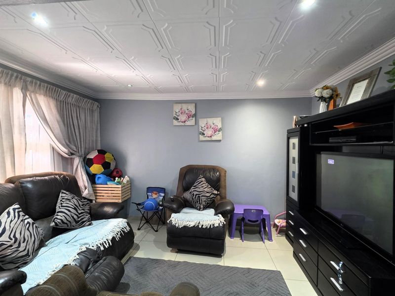 A living room featuring tiled flooring, decorative ceiling tiles, and recessed downlighting, providing a functional space for relaxation.