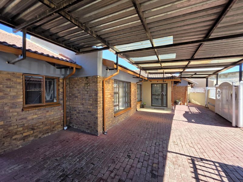 A covered outdoor patio area featuring facebrick walls, durable brick paving, and a corrugated metal roof structure.