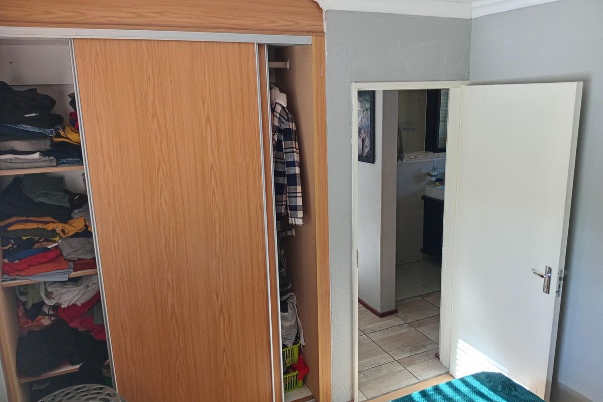 Bedroom featuring built-in wooden sliding door cupboards and direct access to an en-suite bathroom.