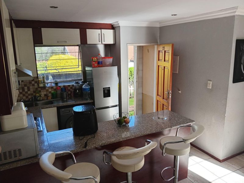 Compact kitchen featuring granite countertops, breakfast bar, built-in cabinetry, and direct access to the exterior.