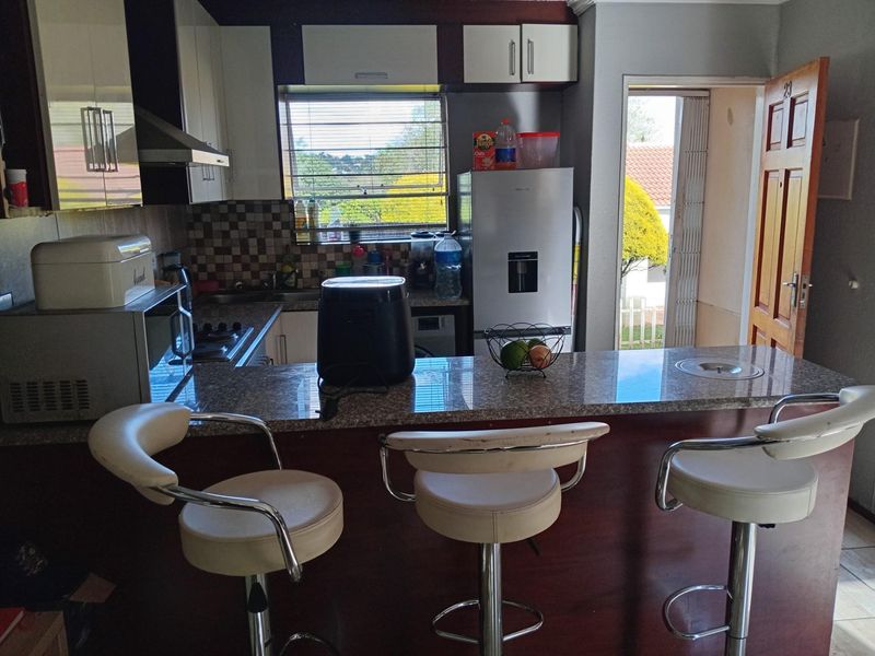 A functional kitchen featuring a granite breakfast bar, built-in cabinetry, and direct access to the exterior.