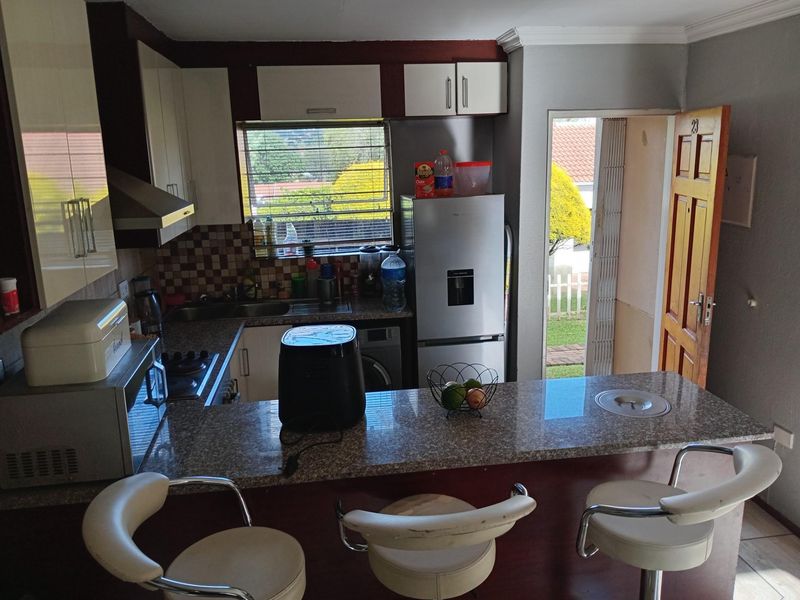 Compact kitchen featuring granite countertops, a breakfast bar, built-in cabinetry, and direct access to the exterior.
