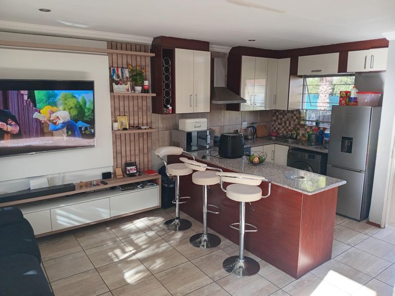 Open-plan living area featuring a modern kitchen with granite countertops, breakfast bar, and integrated cabinetry, seamlessly flowing into the adjacent lounge space.