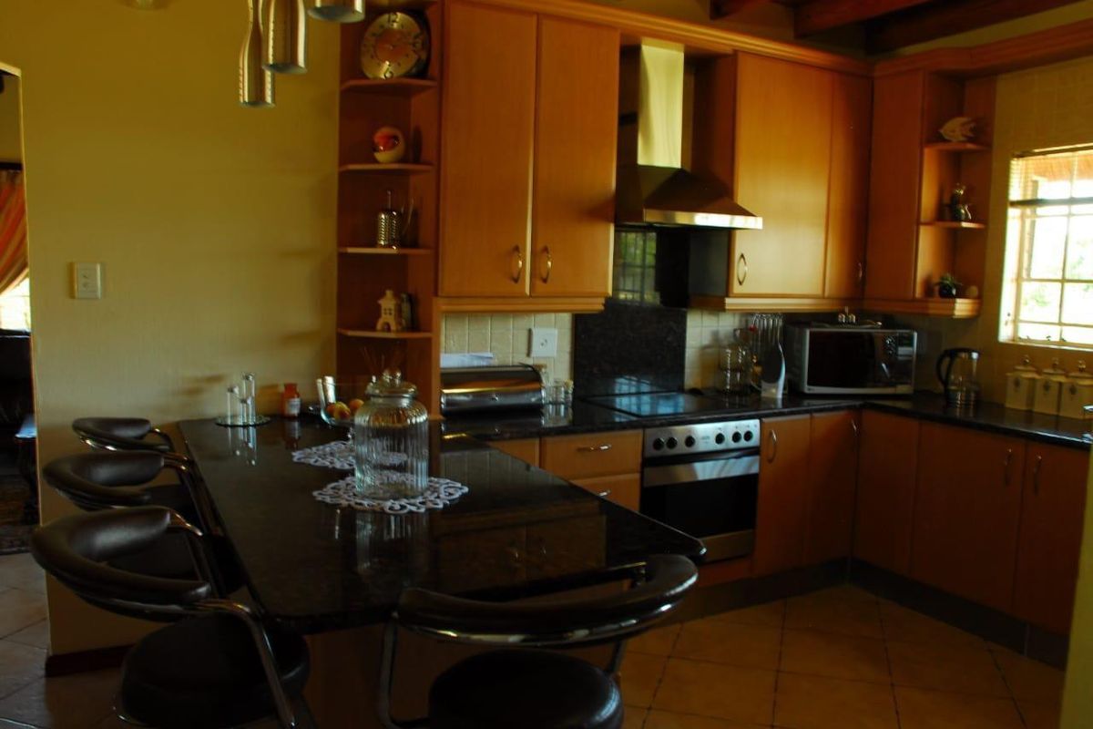 A functional kitchen featuring wooden cabinetry, dark granite countertops, a built-in oven, extractor fan, and a breakfast bar island.