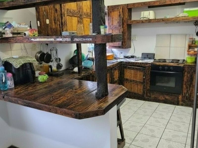 Kitchen featuring rustic dark wood cabinetry, a breakfast bar, built-in oven and hob, and tiled flooring.