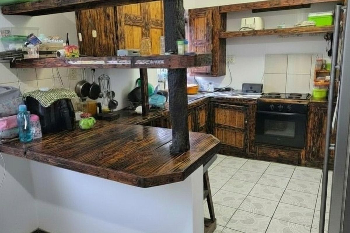 Kitchen featuring rustic dark wood cabinetry, a breakfast bar, built-in oven and hob, and tiled flooring.