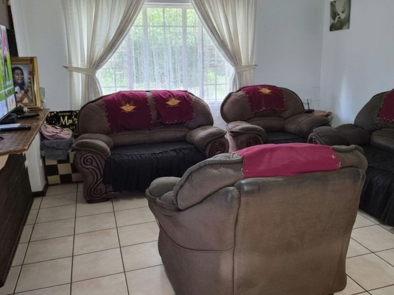 A living room featuring tiled flooring and a large window with curtains, providing a functional space for relaxation.