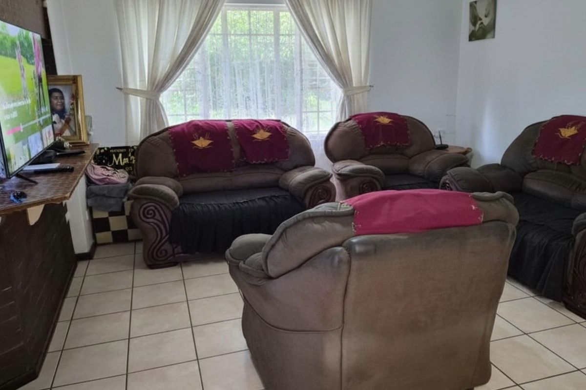 A living room featuring tiled flooring and a large window with curtains, providing a functional space for relaxation.