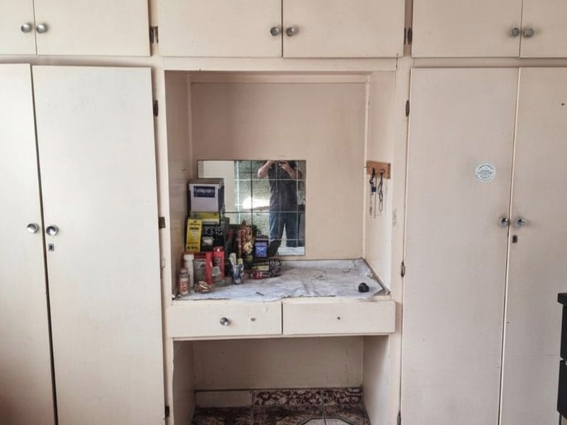 A bedroom featuring built-in floor-to-ceiling cabinetry with a central vanity area and integrated mirror.