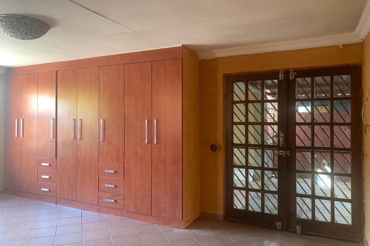 A bedroom featuring extensive built-in wooden cabinetry and a classic timber-framed glass door leading to an outdoor area.