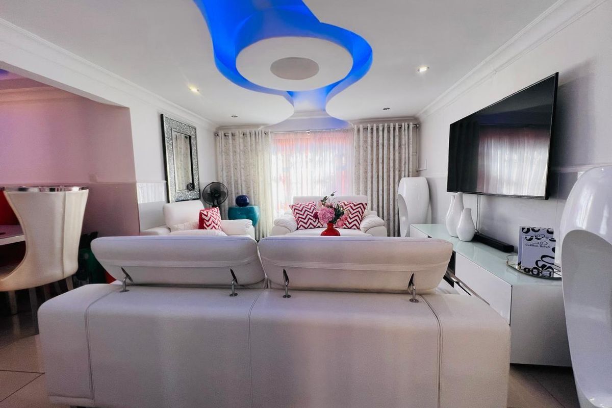A modern living room featuring a distinctive recessed ceiling design with integrated blue LED lighting and tiled flooring.