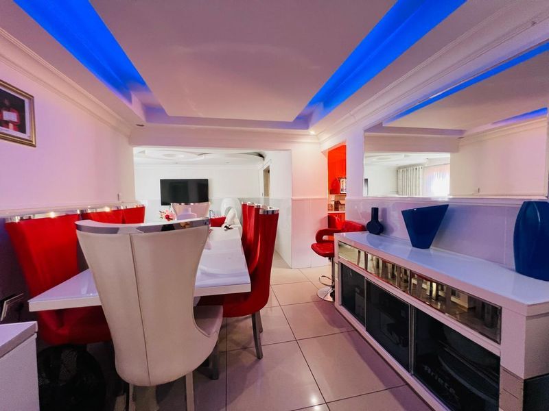 Open plan dining area featuring a modern tray ceiling with integrated blue LED lighting and tiled flooring.