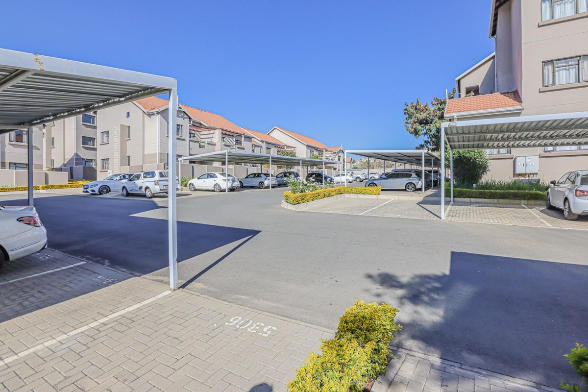 A well-maintained apartment complex parking area featuring covered carports, paved driveways, and neat landscaping.