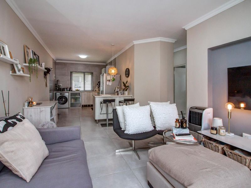Open plan living area featuring a modern kitchen with integrated laundry space, tiled flooring, and a recessed media wall.