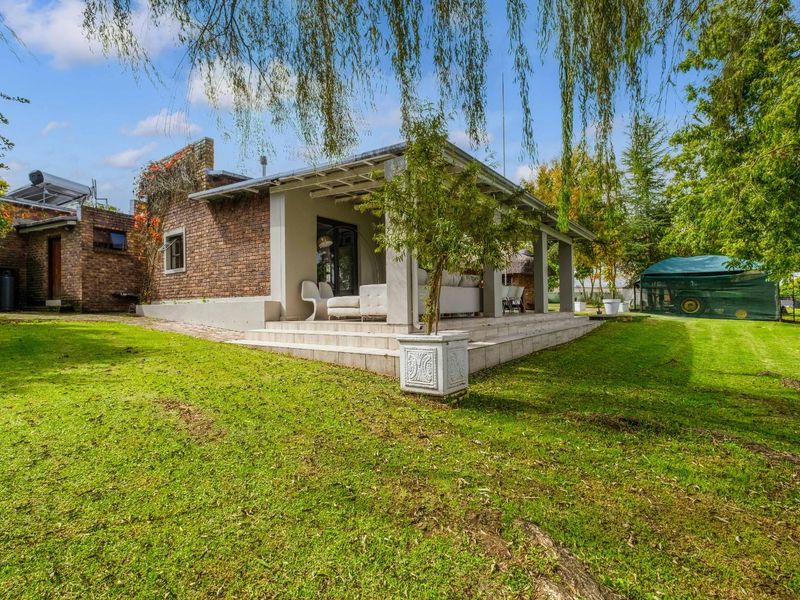 A view of the rear exterior featuring a covered patio, brick facade, and a spacious, well-maintained garden area.