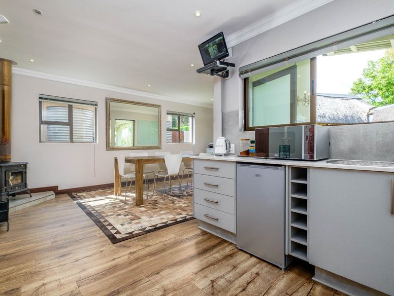Open plan living and dining area featuring a wood-burning fireplace, modern cabinetry, and wood-look flooring with direct access to the kitchen space.