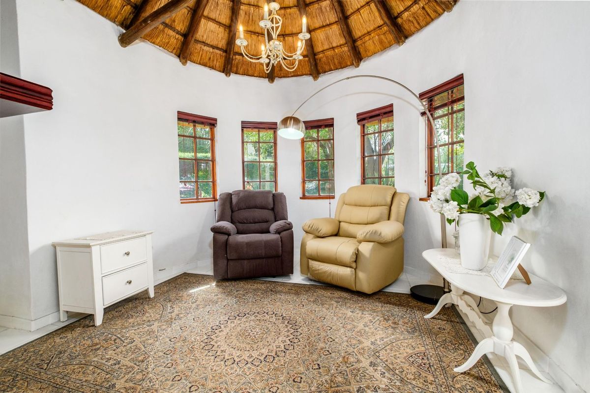A circular living area featuring a traditional thatched roof, exposed timber beams, and multiple windows providing natural light.